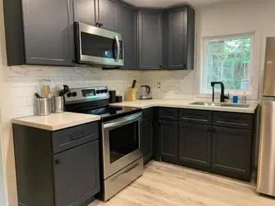 a kitchen with black cabinets and stainless steel appliances at County Cove - Wellington Suite - Two-Bedroom Wellington Apartment in Wellington