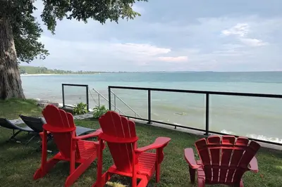 three red chairs sitting next to the ocean at Sakura Cottage - Serenity on PEC Waterfront in Wellington