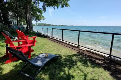 a group of chairs sitting next to the water at Sakura Cottage - Serenity on PEC Waterfront in Wellington