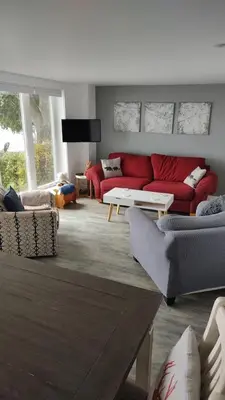 a living room with a red couch and a table at Sakura Cottage - Serenity on PEC Waterfront in Wellington