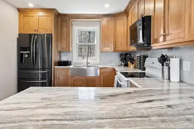 a kitchen with wooden cabinets and a marble counter top at Muskoka Charm Beautiful four bedroom cottage in Gravenhurst