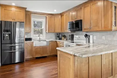 a kitchen with wooden cabinets and a stainless steel refrigerator at Muskoka Charm Beautiful four bedroom cottage in Gravenhurst