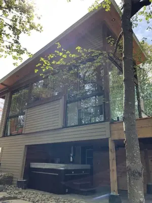 a house with a bench in front of a tree at Muskoka Charm Beautiful four bedroom cottage in Gravenhurst