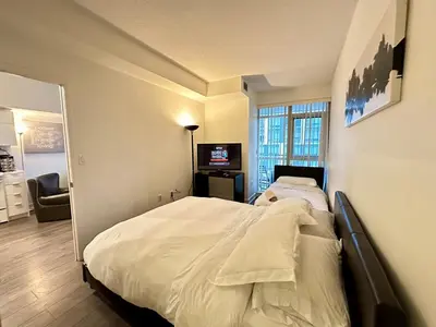 a bedroom with a large bed and a television at Comfy 1Bdrm den 2Baths with 3 real beds plus parking in Toronto