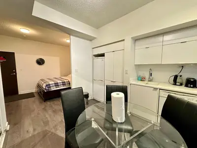 a kitchen with a glass table and chairs in a room at Comfy 1Bdrm den 2Baths with 3 real beds plus parking in Toronto