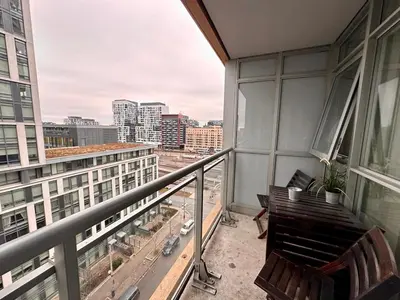 a balcony with two chairs and a view of a city at Comfy 1Bdrm den 2Baths with 3 real beds plus parking in Toronto