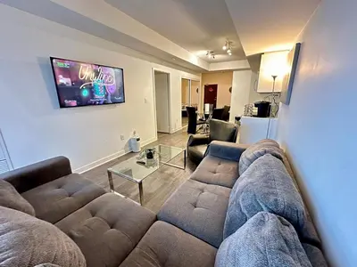 a living room with a couch and a tv at Comfy 1Bdrm den 2Baths with 3 real beds plus parking in Toronto