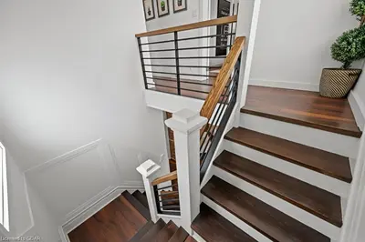 a stairwell with white walls and wood floors at 4 Bedroom Luxury House, Free Parking, Next to LRT, Kitchener Downtown, near Chicopee Ski Club in Kitchener