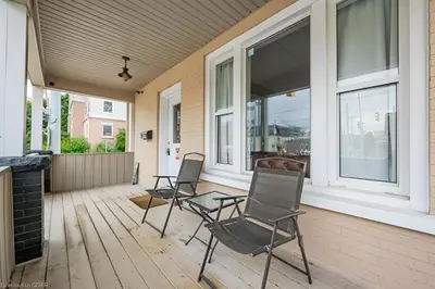 a porch with three chairs and a table and windows at 4 Bedroom Luxury House, Free Parking, Next to LRT, Kitchener Downtown, near Chicopee Ski Club in Kitchener