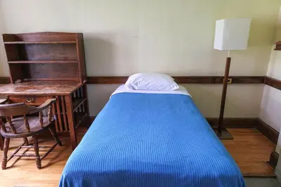 a small bedroom with a blue bed and a desk at Knox Residence - University of Toronto in Toronto