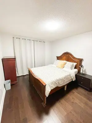 a bedroom with a bed and a dresser in it at Supreme Suites in Ajax