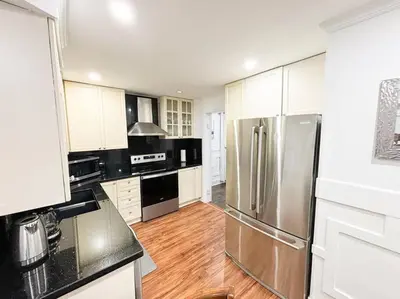 a kitchen with a stainless steel refrigerator and white cabinets at Supreme Suites in Ajax