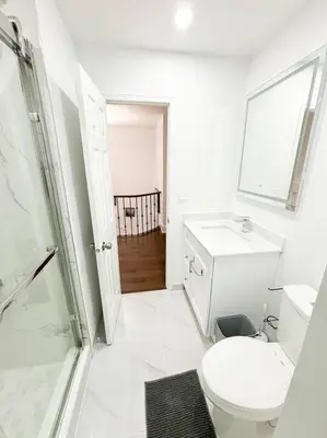 a white bathroom with a toilet and a sink at Supreme Suites in Ajax