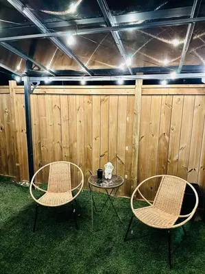 two chairs and a table in front of a fence at Cozy private backyard garden studio in Pickering