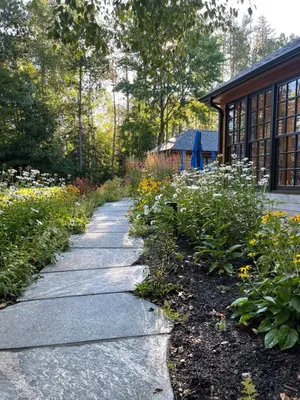 a garden path with flowers in front of a house at Haliburton Post House in Minden