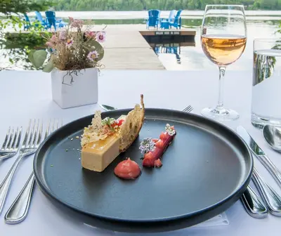 a plate of food on a table with a glass of wine at Haliburton Post House in Minden