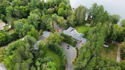 an aerial view of a house in the woods next to the water at Haliburton Post House in Minden