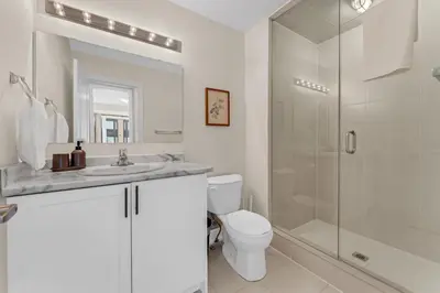 a white bathroom with a shower and a toilet at Bright & Stylish Modern Townhome in Oakville! in Oakville