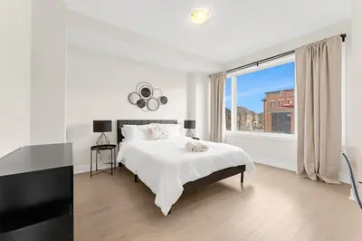 a white bedroom with a bed and a large window at Bright & Stylish Modern Townhome in Oakville! in Oakville