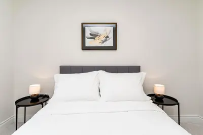 a bedroom with a white bed with two side tables at Bright & Stylish Modern Townhome in Oakville! in Oakville