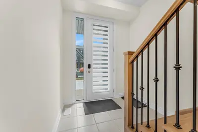 a hallway with a white door and a staircase at Bright & Stylish Modern Townhome in Oakville! in Oakville