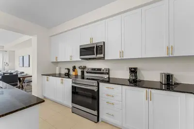 a kitchen with white cabinets and a black stove top oven at Bright & Stylish Modern Townhome in Oakville! in Oakville