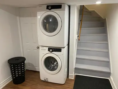 a washer and dryer in a room with a staircase at Adorable 3 Bedroom Apartment with Free Parking in Ajax