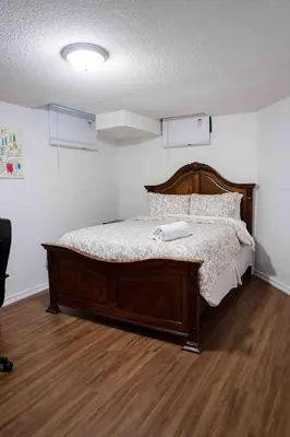 a bed with a wooden frame in a room at Adorable 3 Bedroom Apartment with Free Parking in Ajax