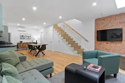 a living room with a couch and a staircase at Chic 2BR Top Floor Retreat with Rooftop Near Subway in Toronto