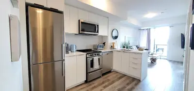 a kitchen with white cabinets and a stainless steel refrigerator at 1 Bedroom condo with balcony Erb St Waterloo in Waterloo