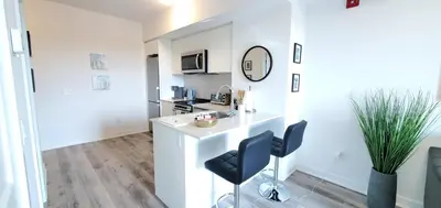 a white kitchen with a counter and two chairs at 1 Bedroom condo with balcony Erb St Waterloo in Waterloo
