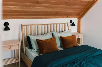 a bedroom with a bed with a wooden headboard and pillows at Camp Haliburton - Waterfront A-Frame in Wilberforce