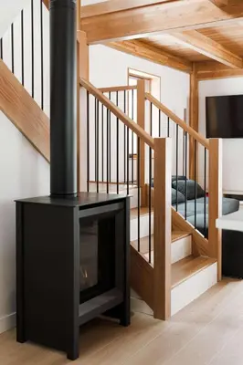 a fireplace in a living room with a staircase at Camp Haliburton - Waterfront A-Frame in Wilberforce