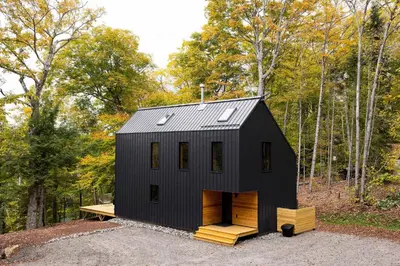 a black tiny house in the woods at Camp Haliburton - Waterfront A-Frame in Wilberforce
