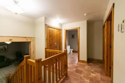 a hallway with a wooden staircase and a bathroom at 5BR Riverfront Retreat w Firetable BBQ and Deck in Orangeville