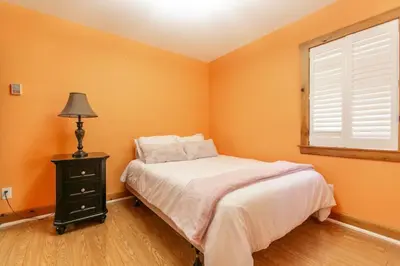 a bedroom with orange walls and a bed and a window at 5BR Riverfront Retreat w Firetable BBQ and Deck in Orangeville