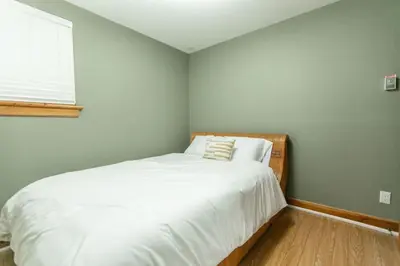 a bedroom with a bed with white sheets and a window at 5BR Riverfront Retreat w Firetable BBQ and Deck in Orangeville