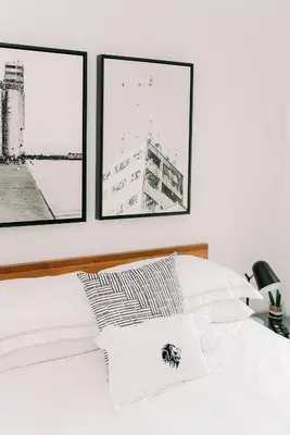 a white bedroom with three pictures on the wall at The VanderMarck Boutique Hotel in Collingwood