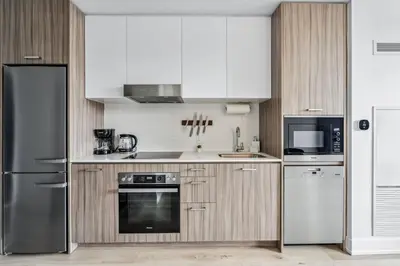 a kitchen with white cabinets and stainless steel appliances at Designer Yonge & Eglinton Gem, Parking, 65 TV in Toronto