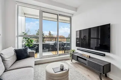 a living room with a large tv and a couch at Designer Yonge & Eglinton Gem, Parking, 65 TV in Toronto