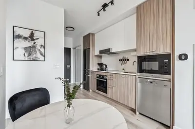 a white kitchen with a white table and black chairs at Designer Yonge & Eglinton Gem, Parking, 65 TV in Toronto