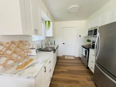 a kitchen with white cabinets and a stainless steel refrigerator at Lovely Beachside Oasis 2BD in Port Dover in Port Dover