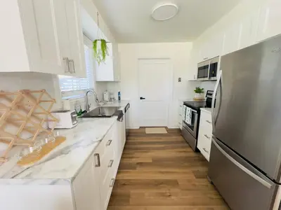 a kitchen with white cabinets and a stainless steel refrigerator at Lovely Beachside Oasis 2BD in Port Dover in Port Dover