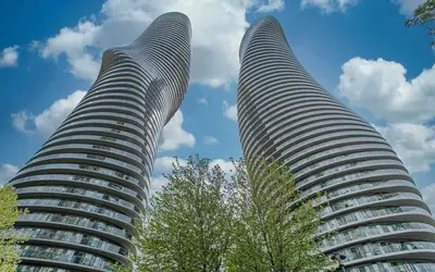 two tall buildings with trees in front of a blue sky at 2 Bedroom 1 Bathroom renovated fully furnished apartment in Mississauga