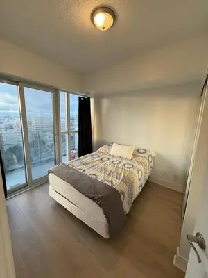 a bedroom with a bed in a room with windows at 2 Bedroom 1 Bathroom renovated fully furnished apartment in Mississauga