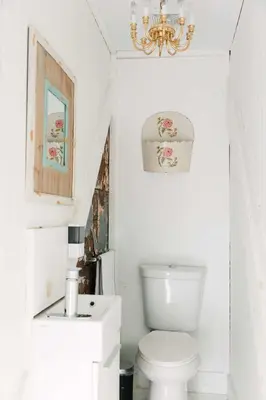 a white bathroom with a toilet and a chandelier at Bloomfield Bliss - Hot Tub and Walking Distance to Park in Bloomfield