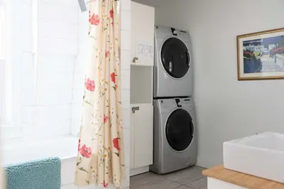 a bathroom with a washing machine and a washer and dryer at Bloomfield Bliss - Hot Tub and Walking Distance to Park in Bloomfield
