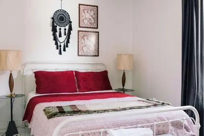 a bedroom with a bed with red pillows and two lamps at Bloomfield Bliss - Hot Tub and Walking Distance to Park in Bloomfield