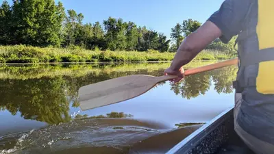 a man holding a paddle in a boat in the water at Niagara Creekside B&B - Waterfront suite in Niagara Falls