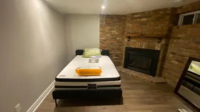 a room with a mattress in front of a fireplace at Cozy Basement in Richmond Hill